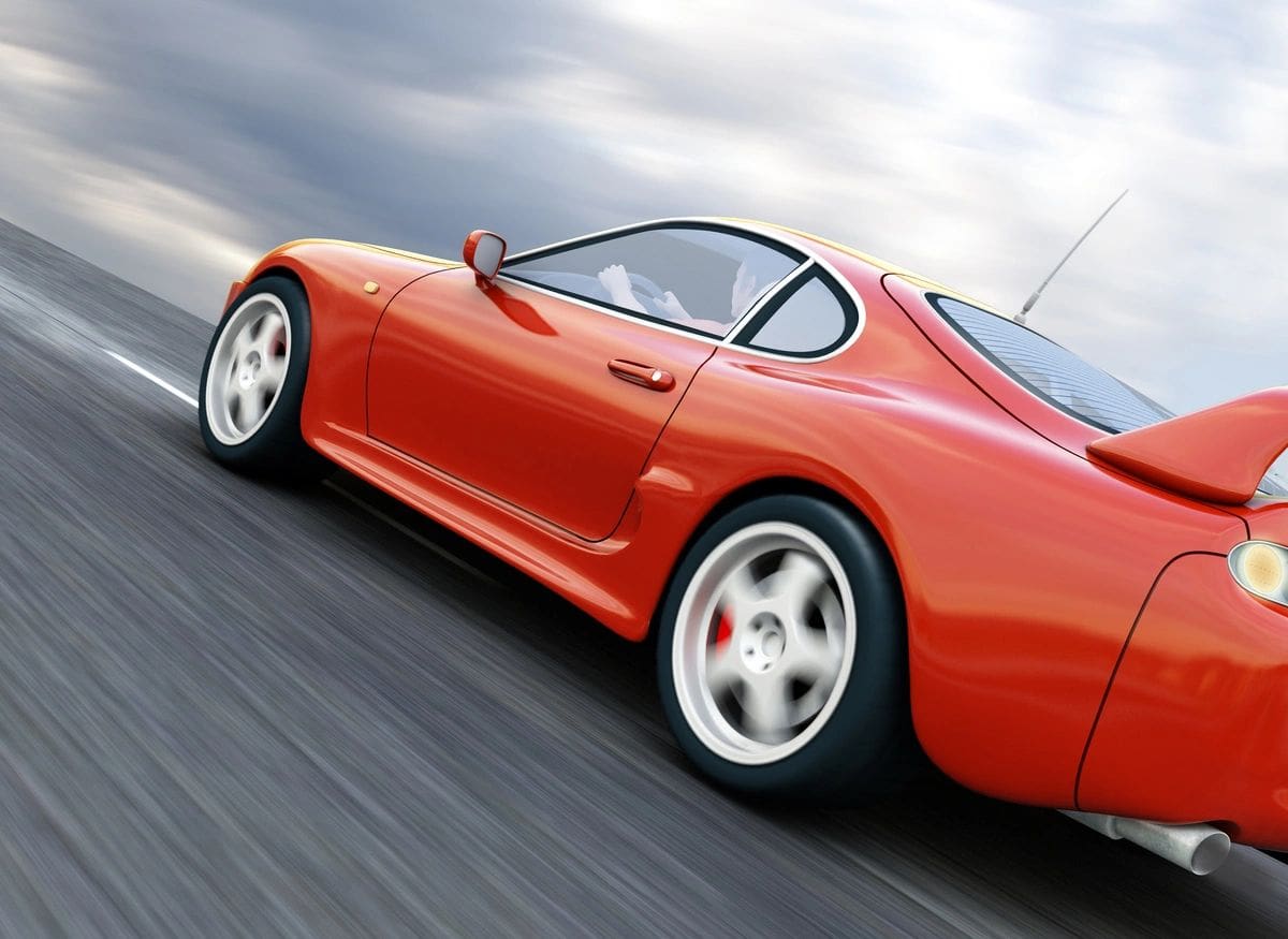 A red sports car driving down the road.