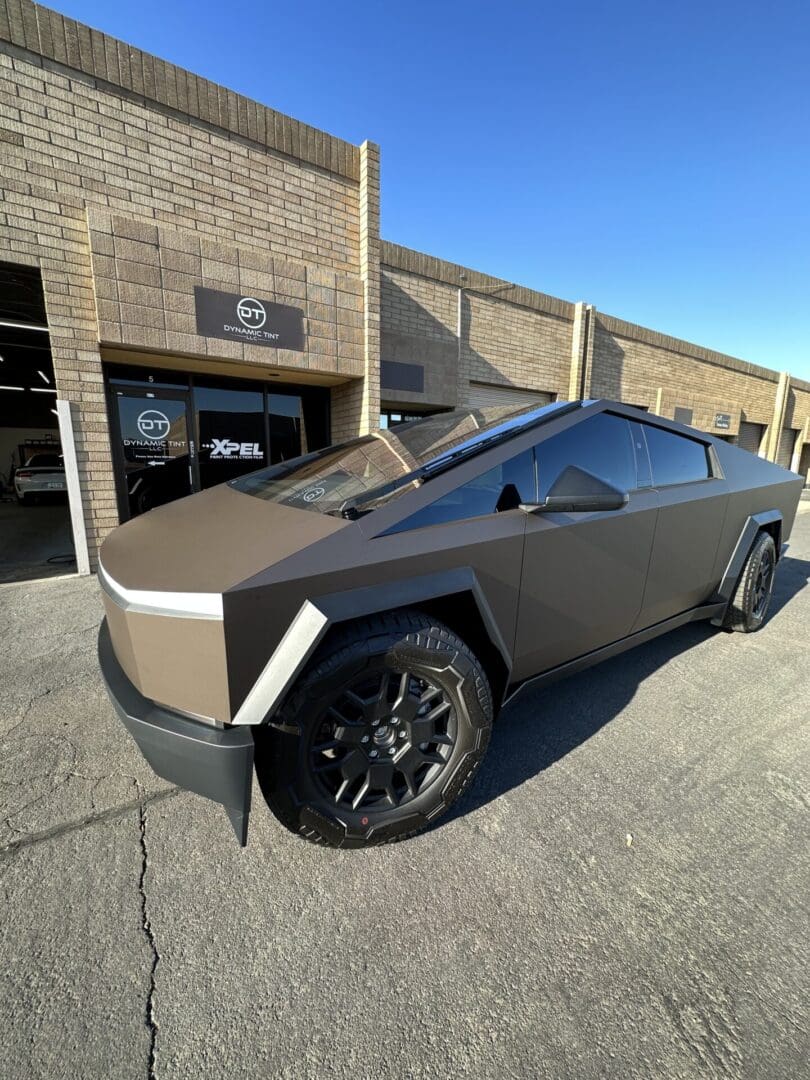 A brown car parked in front of a building.