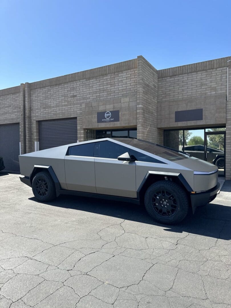 A silver truck parked in front of a building.