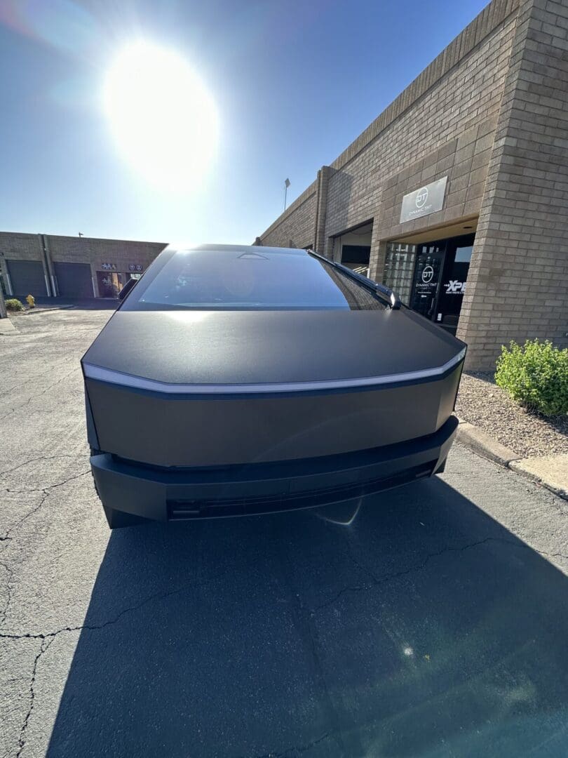 A car parked in front of a building with the sun shining.