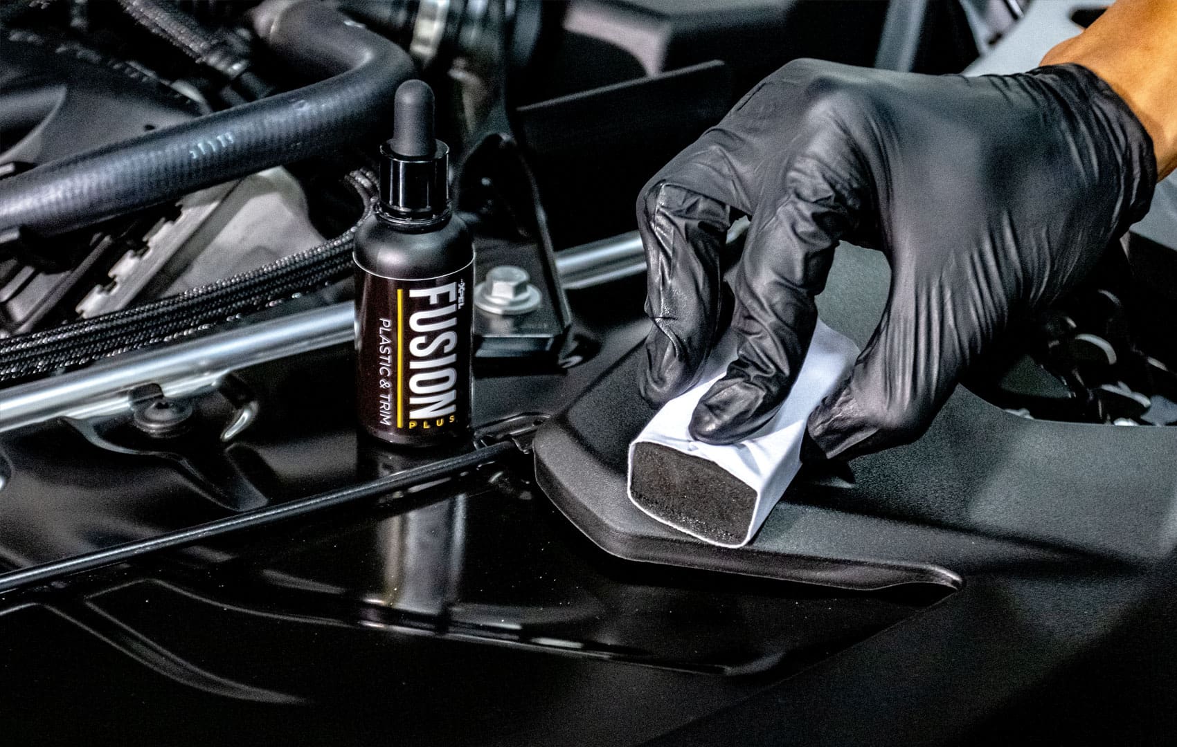 A person in black gloves cleaning the seat of a motorcycle.